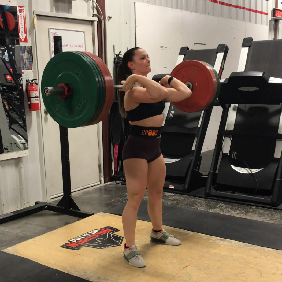 IRON COMPANY Athlete Kyra Milligan performing heavy barbell back squats with rubber bumper plates and an Olympic bar