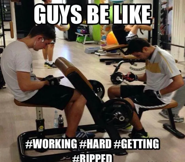 Two gym users looking at phones between exercises