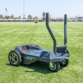 BodyKore All Terrain Magnetic Resistance Smart Sled Pro positioned on a turf field, showcasing outdoor use, Bluetooth controls, and heavy-duty wheels for multi-surface performance