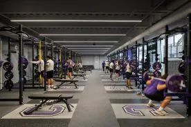 High-performance weight room with Regupol Aktiv rolled rubber flooring, custom logo platforms, and power racks for strength training.