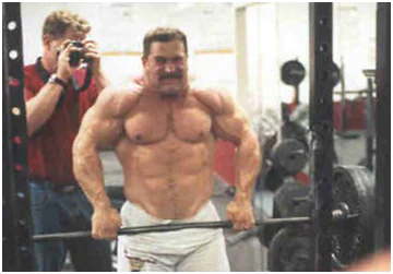 Kirk Karwoski performing thumbless barbell shrugs in gym
