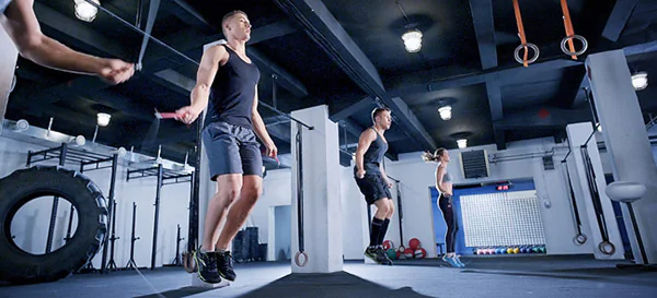 People in a CrossFit box shown jumping rope as part of a cardio training workout.