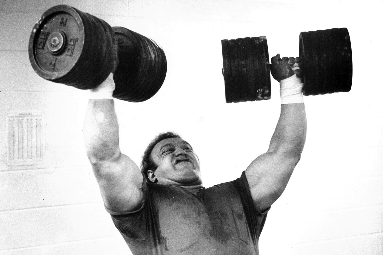 Bill Kazmaier performing an overhead dumbbell press