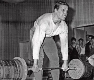 Young strength athlete deadlifting a heavy loaded barbell