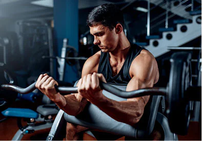 Man in Gym doing preacher curls with barbell