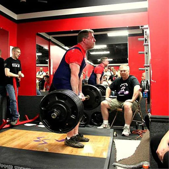 IRON COMPANY athlete Marty Gallagher performing a barbell deadlift on a weightlifting platform.