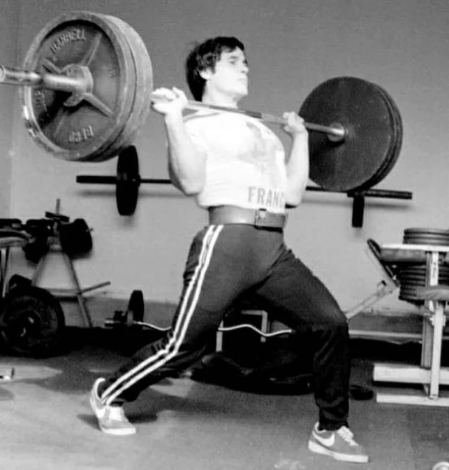 Franco Columbu power cleaning a 315 lb barbell using the shallowest of splits