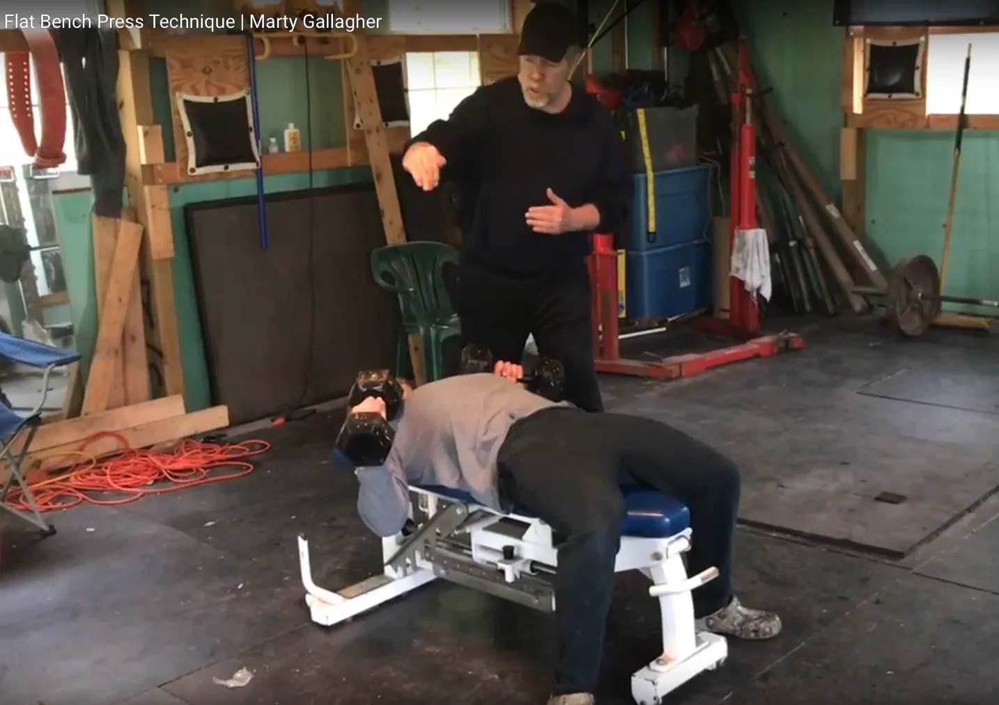 Coach instructing a lifter on flat dumbbell bench press