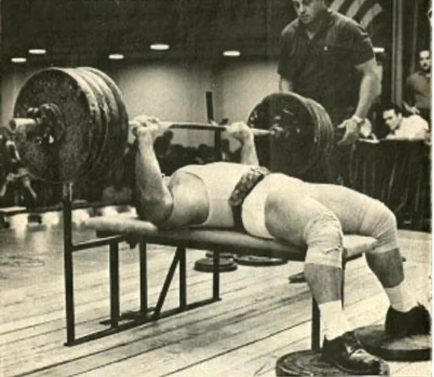 Mel Hennessey bench pressing heavy weight in street shoes