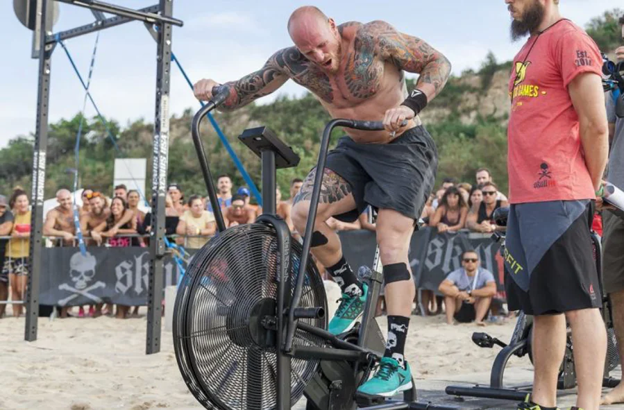 Man performing quad-limb cardio training on a fan bike